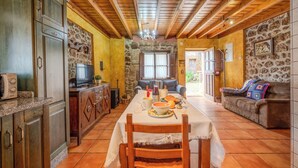A rustic dining area with a wooden table set for four, surrounded by stone walls and wooden beams. - Casa Dolores for 6 people (Cabrales)