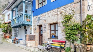 A quaint building with a blue balcony, a stone facade, and a colorful bench outside. - Casa Dolores for 6 people (Cabrales)
