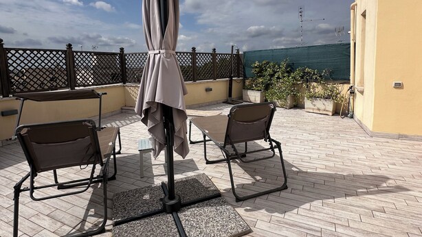 Un patio al aire libre con dos sillones de descanso, una mesa y una sombrilla.