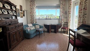 Una sala de estar con un sofá, una mesa de centro, un aparador de madera y un ventanal con cortinas.