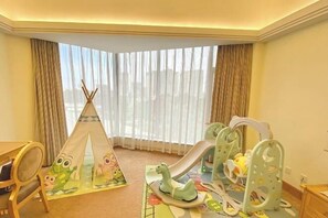 Habitación para niños con zona de juegos que incluye una tienda de campaña, un tobogán y una mecedora.