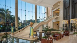 Um hall espaçoso com escadaria central, paredes de vidro e um espelho d'água.