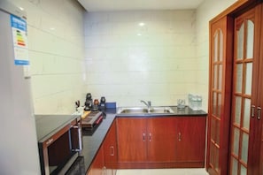 Cocina pequeña con microondas, lavabo y armarios de madera.