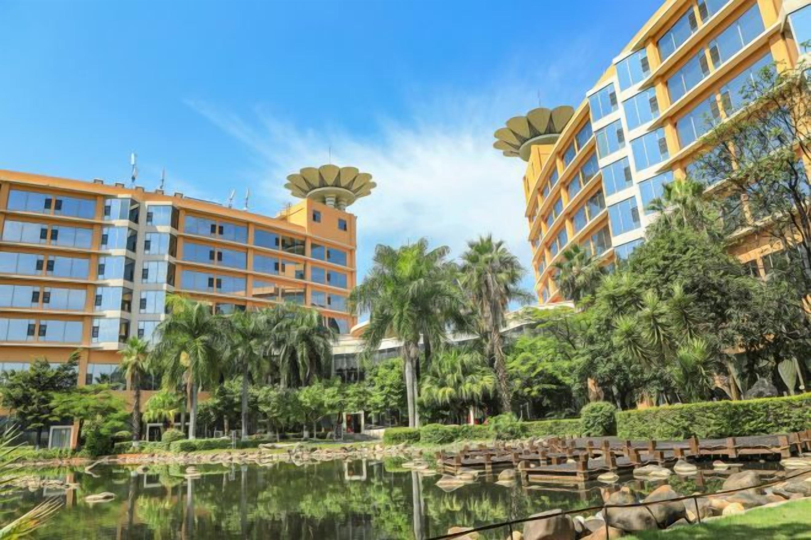 A hotel with multiple floors, a central courtyard with a water feature, and surrounding greenery.