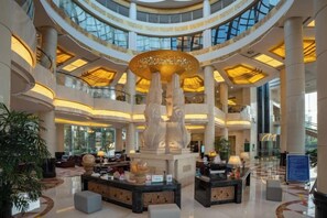 A spacious lobby with a central sculpture, multiple seating areas, and a high ceiling with skylights. - Honghe Guanfang Hotel (Mengzi)