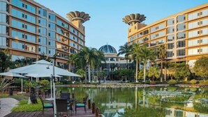 Um hotel com uma estrutura central em forma de cúpula, rodeado por edifícios modernos com varandas.