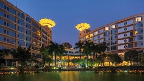 Um hotel com vários andares, um pátio central e um corpo d'água refletindo as luzes.