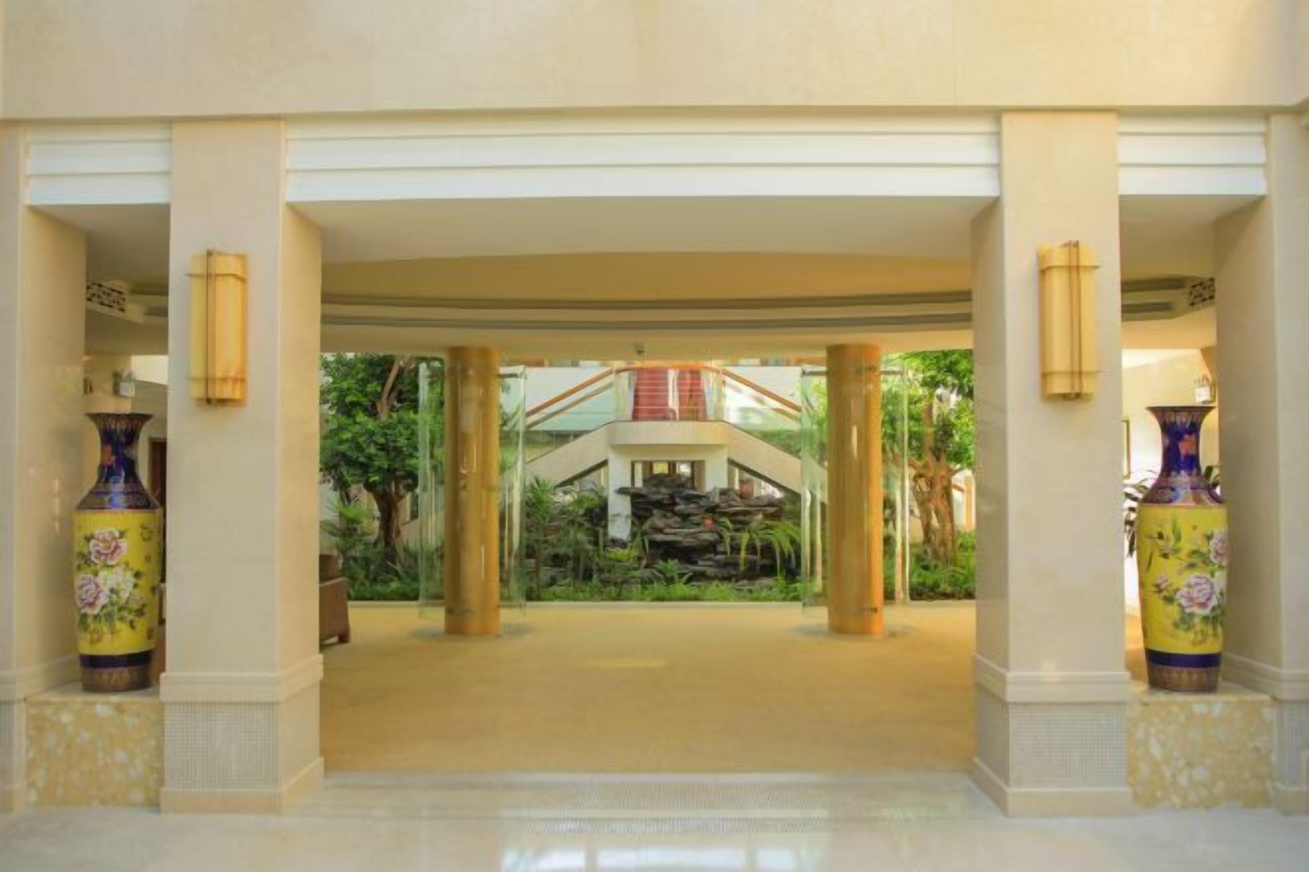A spacious lobby with a central water feature, columns, and large vases.