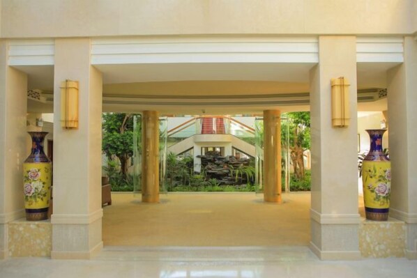 A spacious lobby with a central water feature, columns, and large vases.