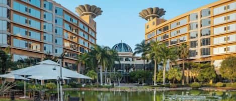 Un hotel con piscina, mobiliario exterior y un edificio de forma abovedada al fondo.