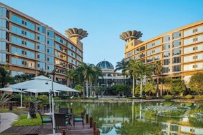 A hotel with a pool, outdoor seating, and a dome-shaped building in the background. - Honghe Guanfang Hotel (Mengzi)