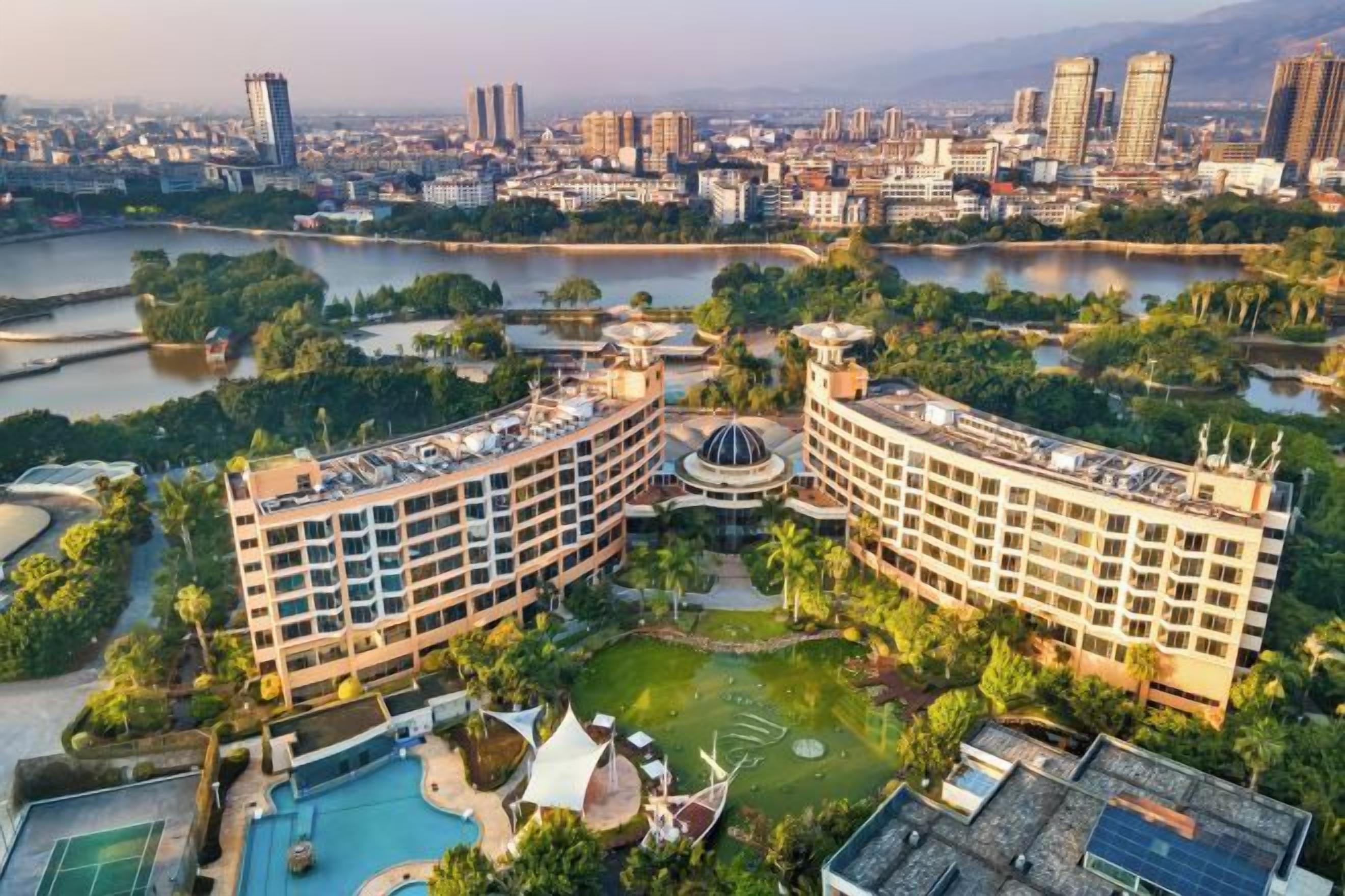 A hotel with a pool, garden, and views of a cityscape.