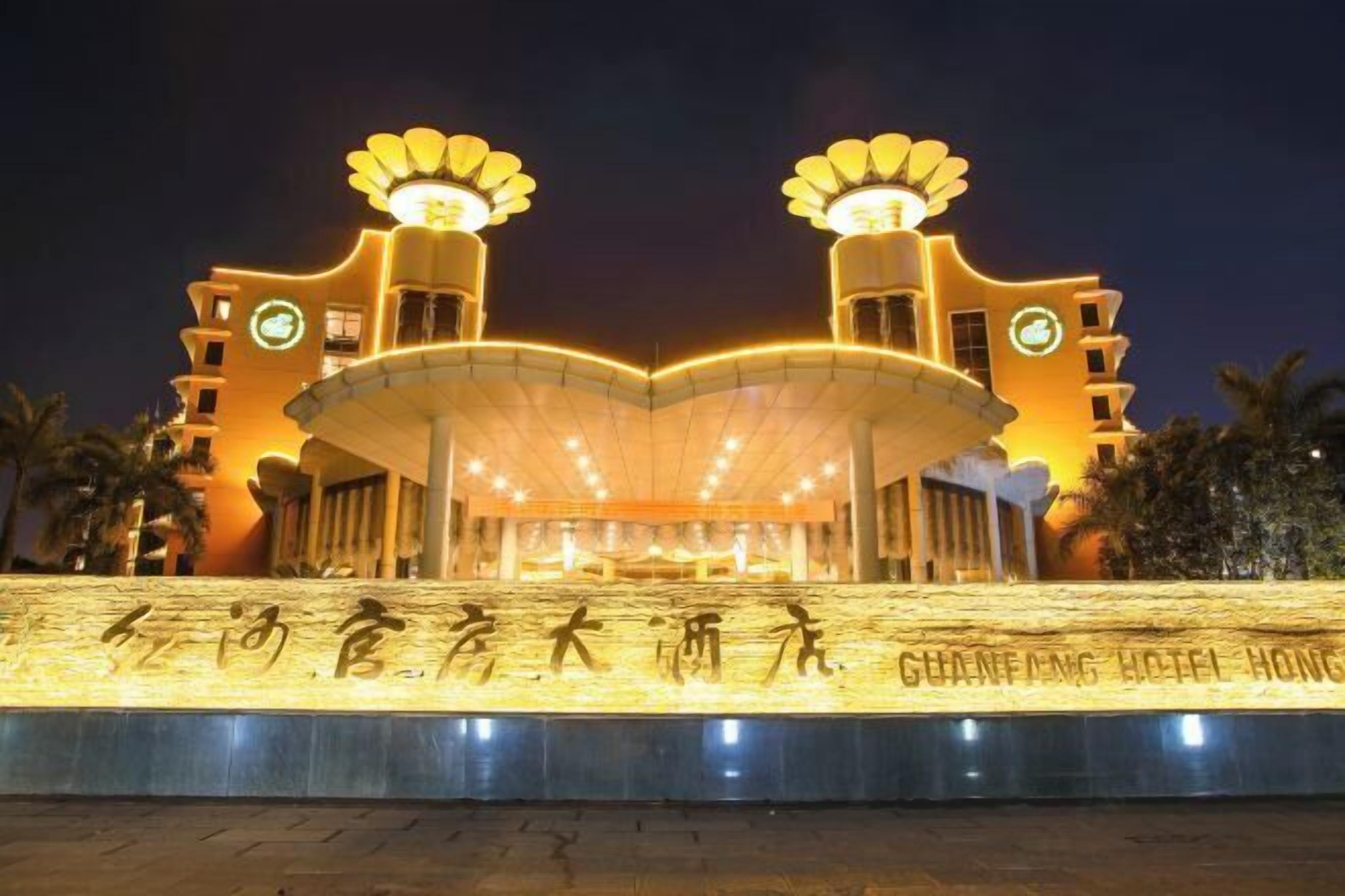 A hotel entrance with a large, illuminated sign and two prominent light fixtures.