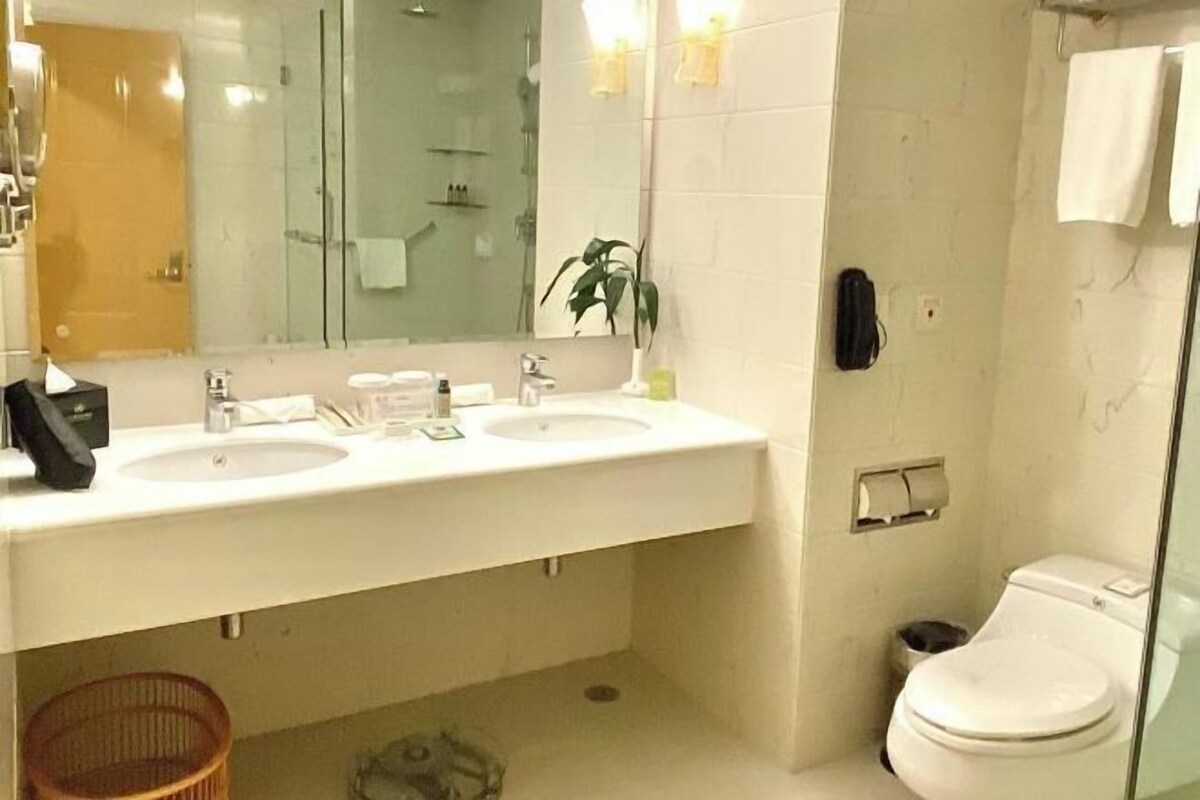 Un baño con dos lavamanos, un espejo, inodoro y zona de ducha.