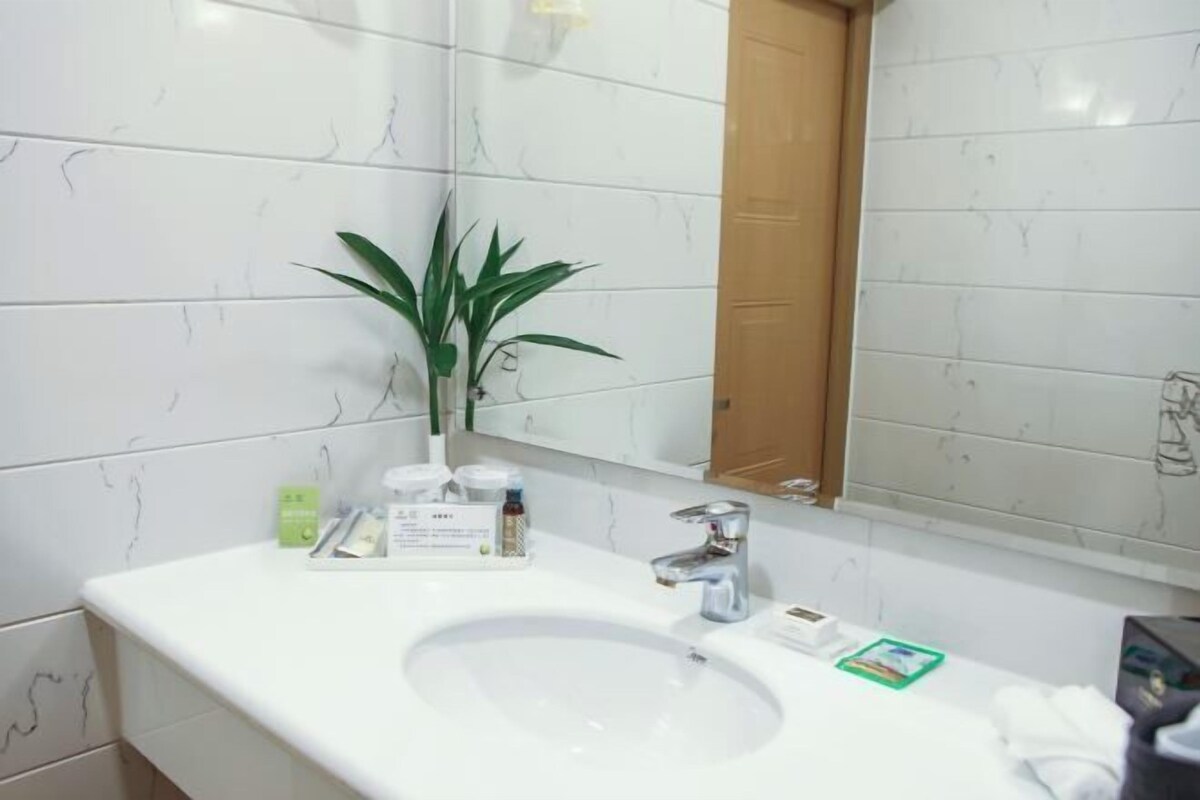 Un baño con un lavamanos blanco, un espejo y una planta en maceta.
