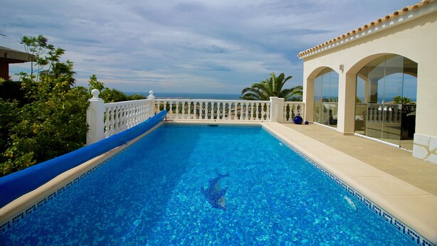 A clear blue pool with a white balustrade, a glass door, and a view of the ocean. - Quiet house and panoramic views  (Denia)