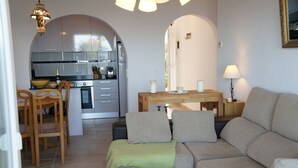 A modern living room with a sofa, a glass coffee table, and a dining area with a wooden table and chairs. - Quiet house and panoramic views  (Denia)