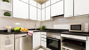 Een moderne keuken met witte kasten, roestvrijstalen apparatuur en een zwart aanrecht.