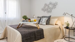 Een keurig opgemaakt slaapkamer met een bed, nachtkastje, lamp en decoratieve muurkunst.