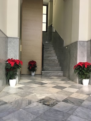 Stunning staircase flanked by lush greenery, set against a backdrop of marble and textured paneling.