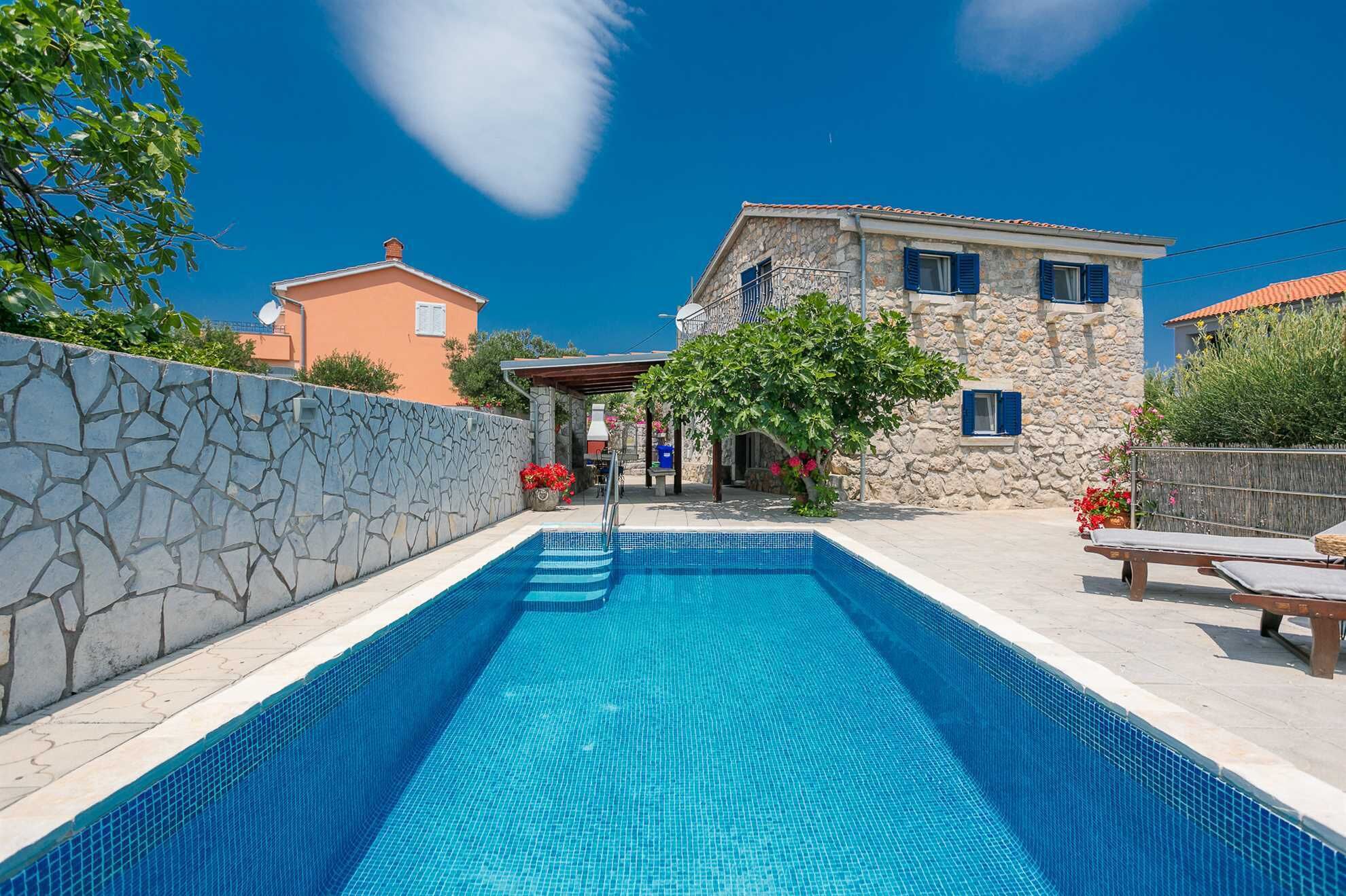 A swimming pool with stone walls and a stone building in the background.