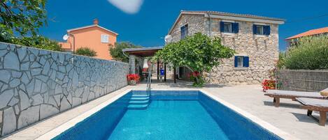 A swimming pool with stone walls and a stone building in the background.