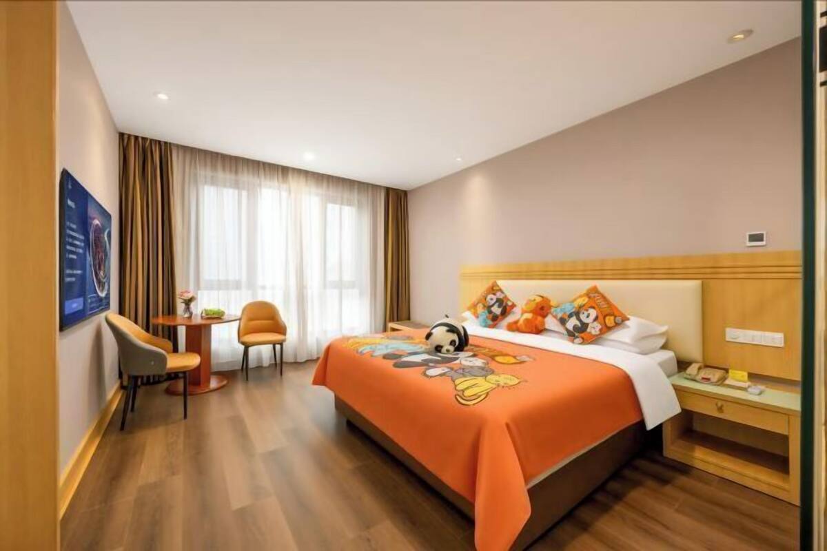 A hotel room with a bed, a desk, a chair, and a window with curtains.