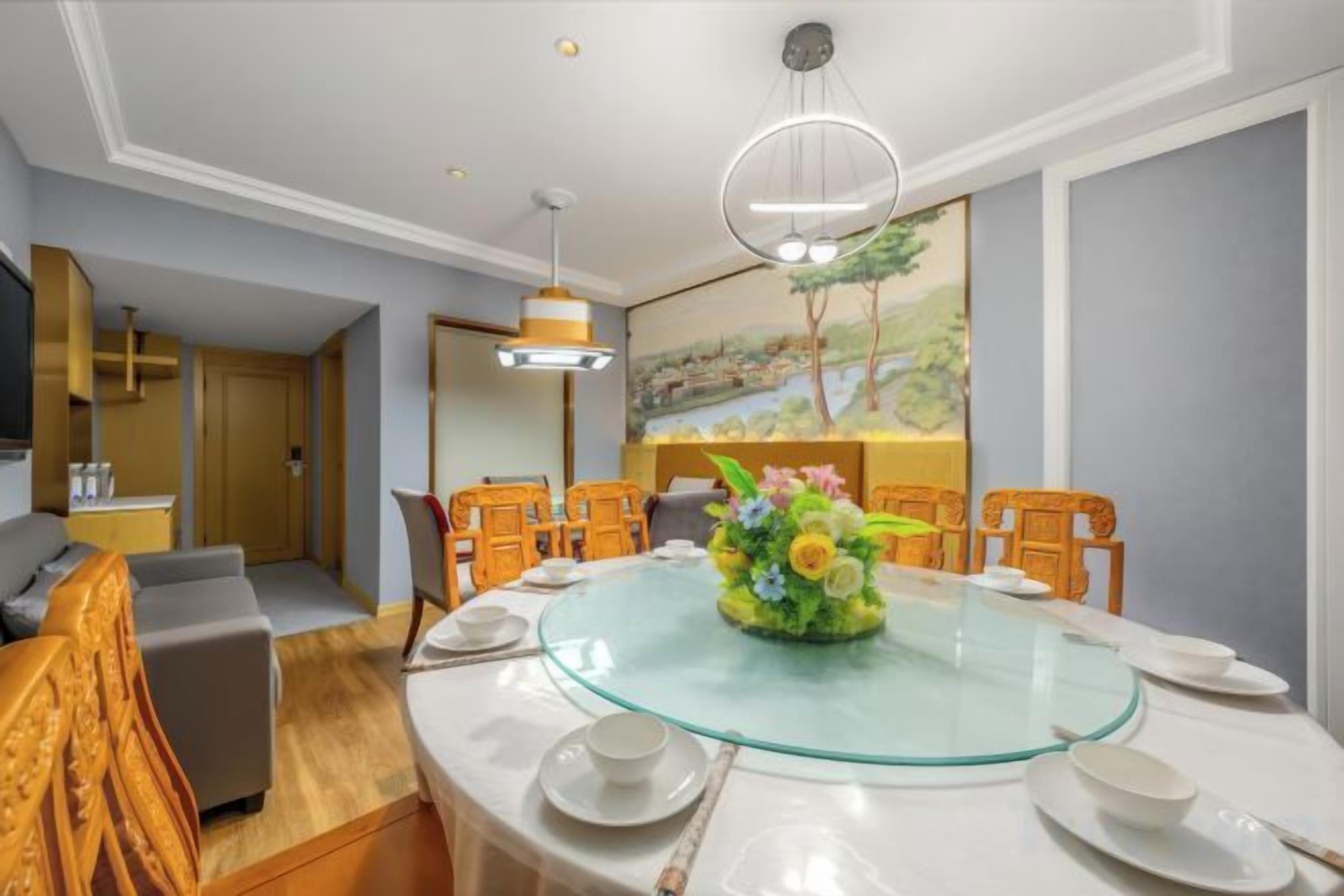 Un coin repas avec une table en verre entourée de chaises, un arrangement floral au centre et un tableau accroché au mur.