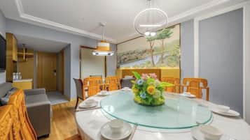 A dining area with a glass table surrounded by chairs, a floral centerpiece, and a painting on the wall.
