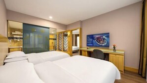 Habitación de hotel con dos camas, un escritorio, una computadora y un espejo grande.