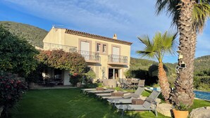 A two-story house with a balcony, a swimming pool, and a well-maintained lawn.