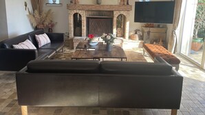 A living room with a fireplace, a large clock, and a TV.