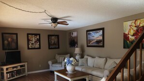 A living room with a wooden floor, a ceiling fan, a sofa set, a coffee table, and a TV stand. - All inclusive, 2 bed 2 bath, pool, perfect location!  (Fort Myers)