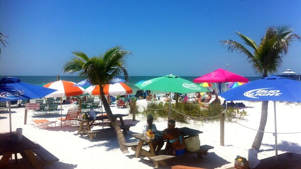 A beach with colorful umbrellas, palm trees, and beach chairs. - All inclusive, 2 bed 2 bath, pool, perfect location!  (Fort Myers)