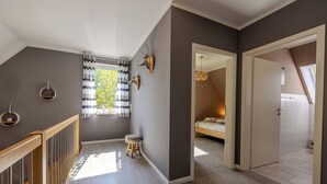 A modern interior with a staircase, a window with curtains, and a bed in the adjacent room. - Vacation home Hünzingen № 1 (Walsrode)