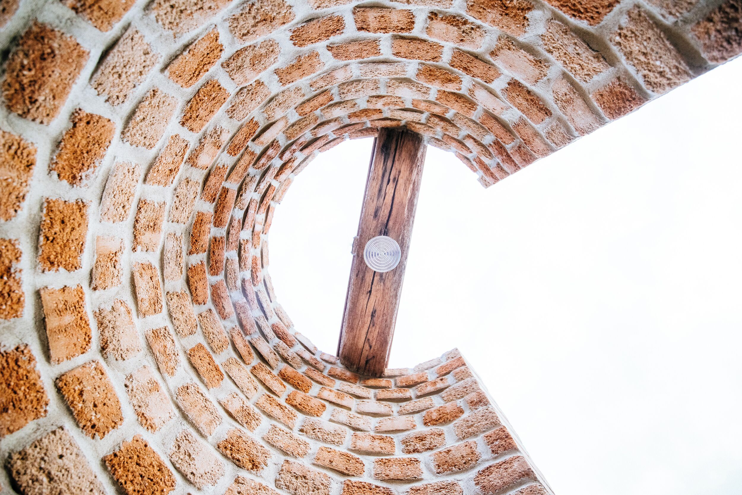 Une structure circulaire en briques, avec un poteau en bois au centre.