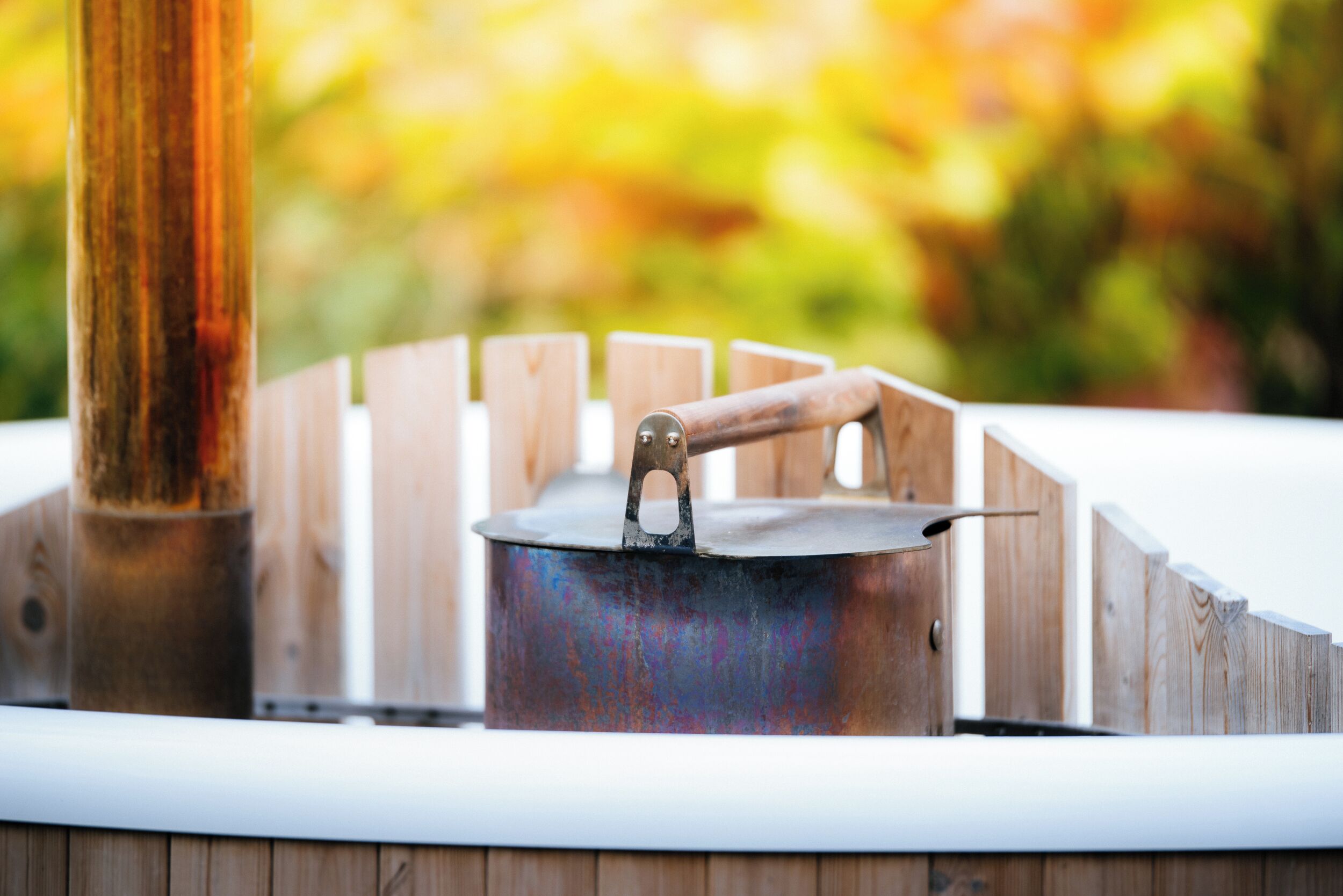 A portable stove with a metal pot on a wooden stand outdoors.