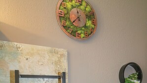 Un mur orné d’une horloge recouverte de mousse, d’un porte-serviettes et de deux jardinières fixées au mur.