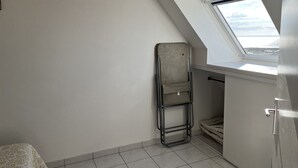 A small, narrow room with a sloped ceiling and a skylight. A metal ladder is leaning against the wall, and a white cabinet is visible. - Apartment with access and stunning sea views (Damgan)