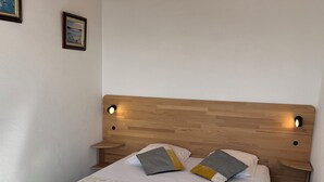 A bedroom with a wooden headboard, a floral bedspread, and two pillows. - Apartment with access and stunning sea views (Damgan)