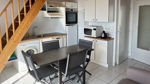 A compact kitchen with a dining table, chairs, a microwave, oven, and a washing machine. - Apartment with access and stunning sea views (Damgan)