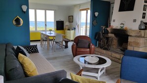 Ein Wohnzimmer mit Sofa, Couchtisch, Kamin und Meerblick.