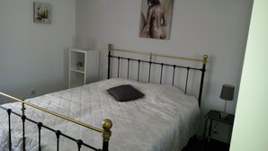 A neatly made bed with a quilted white bedspread and a single black pillow. A painting hangs on the wall above the bed. - APARTMENT IN SAINTE MAXIME (Sainte-Maxime)
