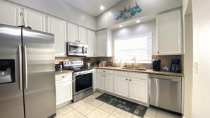 A kitchen with white cabinets, stainless steel appliances, a microwave, oven, and dishwasher.