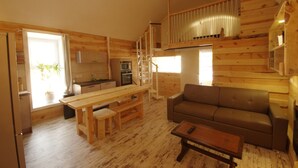 A wooden cabin interior with a kitchen, dining area, and living space.
