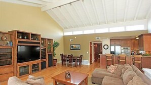 A spacious living room with a large TV, wooden entertainment unit, and comfortable seating.