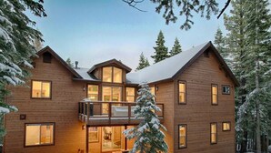 A two-story wooden cabin with a balcony, surrounded by snow-covered trees. - ⭐️Luxury newly built with Sauna, Steam and Hot Tub  (Truckee)