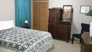 A bedroom with a bed, a wooden dresser, a chair, a mirror, and a wardrobe. - Relax and Rejuvenate in this Peaceful, Wooded Oasis. (Eureka Springs)