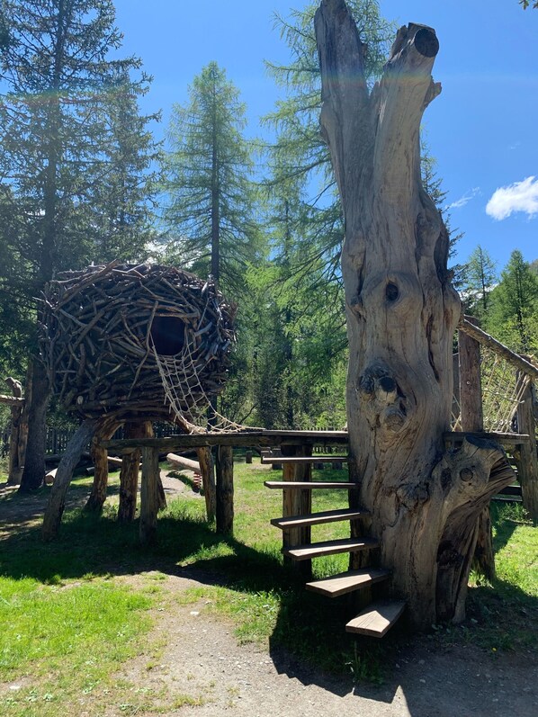 A wooden structure with a rope bridge and a nest-like construction made of branches.