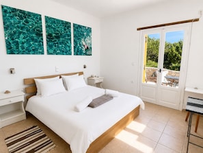 A bedroom with a bed, white walls, a window, and a view of greenery outside. - Hilltop Home Sea Views & Terrace Dining near Aliki (ageria)